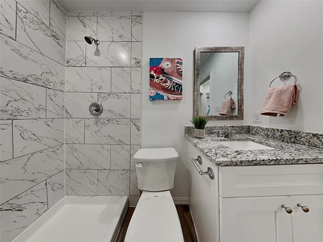 a bathroom with a granite countertop sink a toilet and bathtub