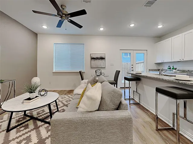 a living room with stainless steel appliances furniture a dining table and kitchen view