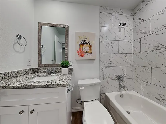 a bathroom with a granite countertop sink a toilet and bathtub