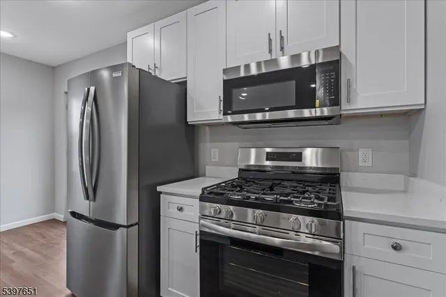 a kitchen with stainless steel appliances white cabinets a stove and a microwave
