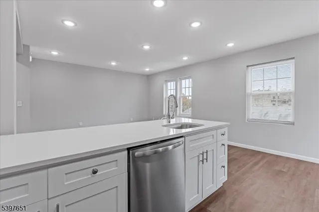 a kitchen with a sink and dishwasher with wooden floor