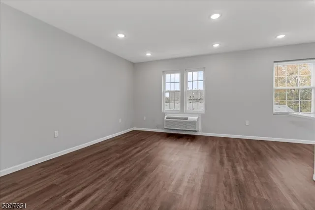 a view of an empty room with wooden floor and window