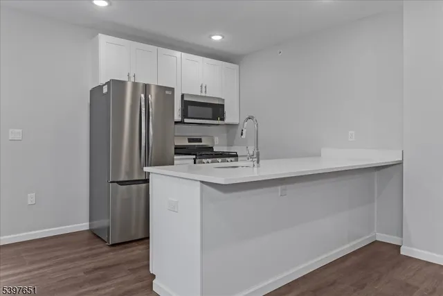 a kitchen with kitchen island a sink stainless steel appliances and wooden floor