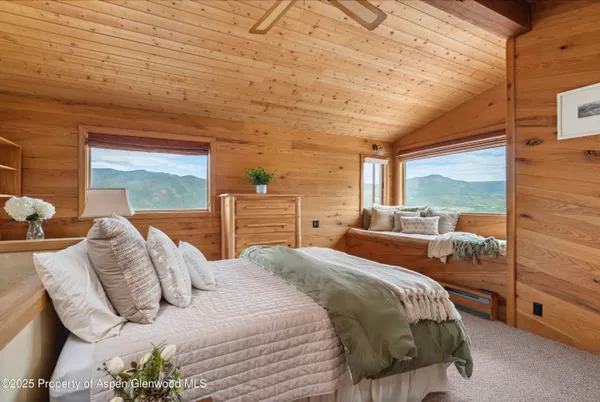 a bedroom with a bed and large windows