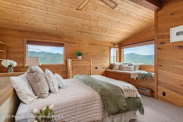 a bedroom with a bed and large windows