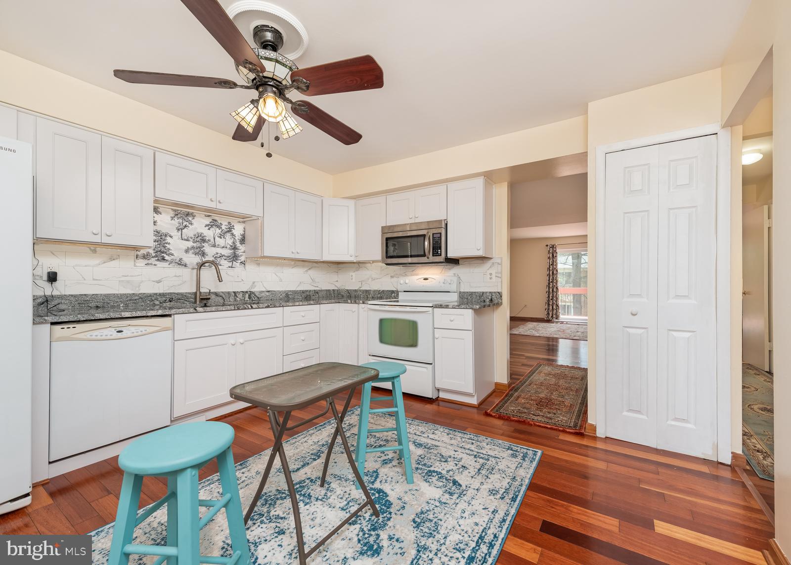 10544 East Wind Way Columbia, MD 21044 - Photo 3 of 42 a kitchen with stainless steel appliances granite countertop a stove top oven a refrigerator a sink and white cabinets with wooden floor