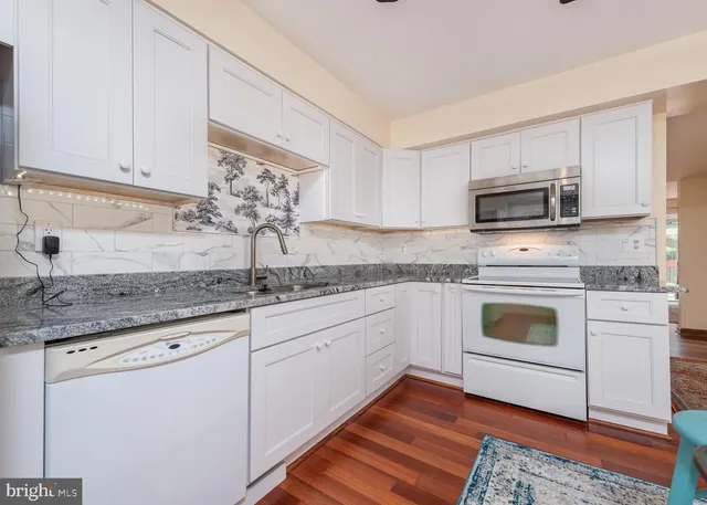 a kitchen with granite countertop a sink cabinets and stainless steel appliances