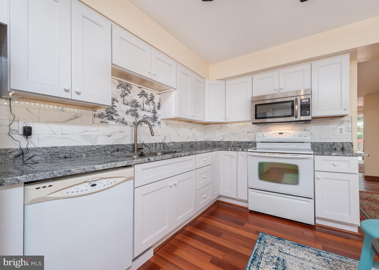 10544 East Wind Way Columbia, MD 21044 - Photo 6 of 42 a kitchen with granite countertop a sink cabinets and stainless steel appliances