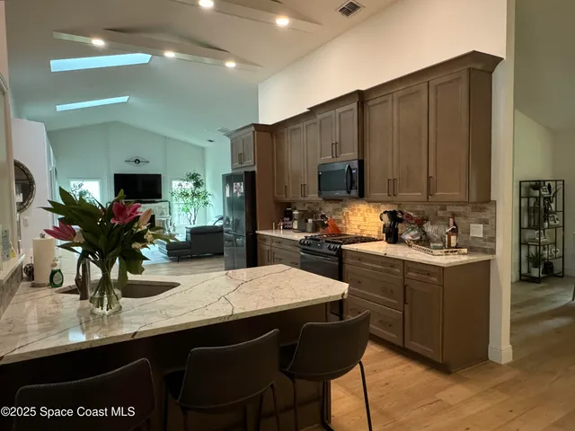 a bedroom with a large bed a flat tv screen and a ceiling fan