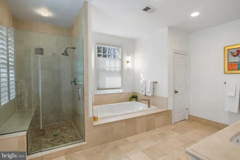 a spacious bathroom with a tub shower and mirror