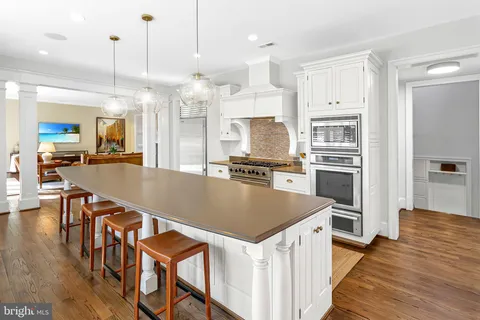 a kitchen with stainless steel appliances granite countertop a refrigerator a stove top oven a sink dishwasher and white cabinets with wooden floor