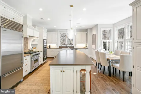 a kitchen with stainless steel appliances granite countertop a stove top oven a sink dishwasher a refrigerator and white cabinets with wooden floor