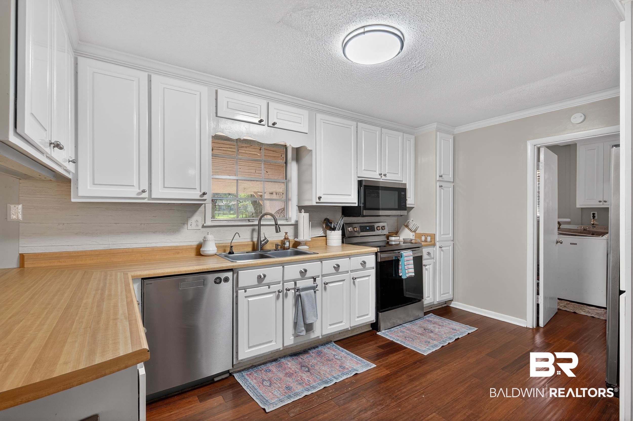 46006 Pecan Lane Bay Minette, AL 36507 - Photo 12 of 40 Kitchen with light countertops, stainless steel appliances, white cabinets, ornamental molding, and a textured ceiling