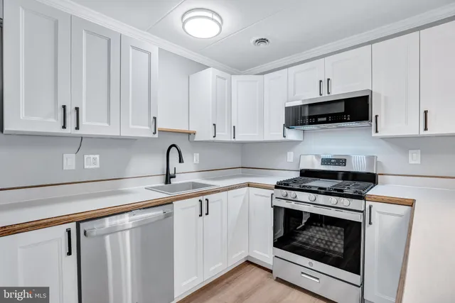 a kitchen with stainless steel appliances granite countertop a stove a white cabinets and a sink