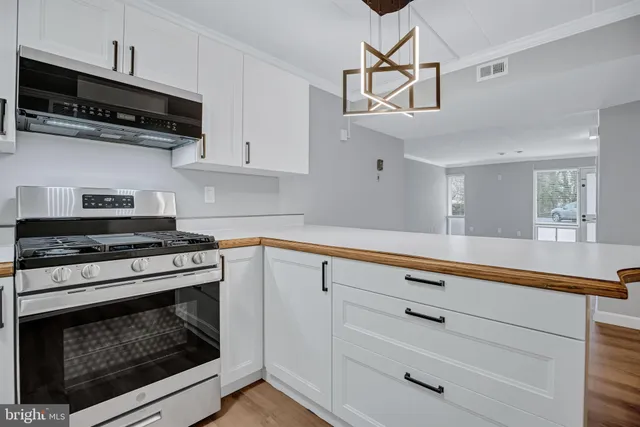 a kitchen with white cabinets stainless steel appliances and wooden floor