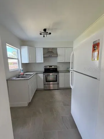 a kitchen with granite countertop a refrigerator and a stove top oven