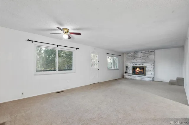 an empty room with windows and fireplace