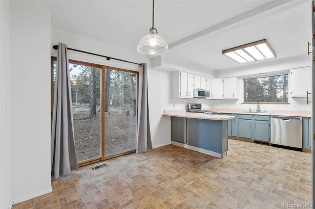 a large kitchen with a window and stainless steel appliances