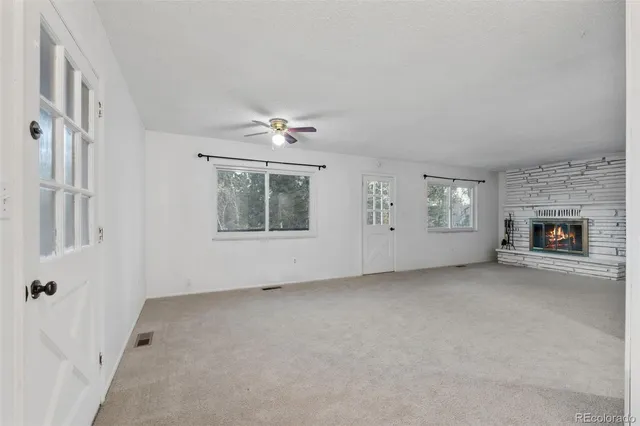 an empty room with windows and fireplace