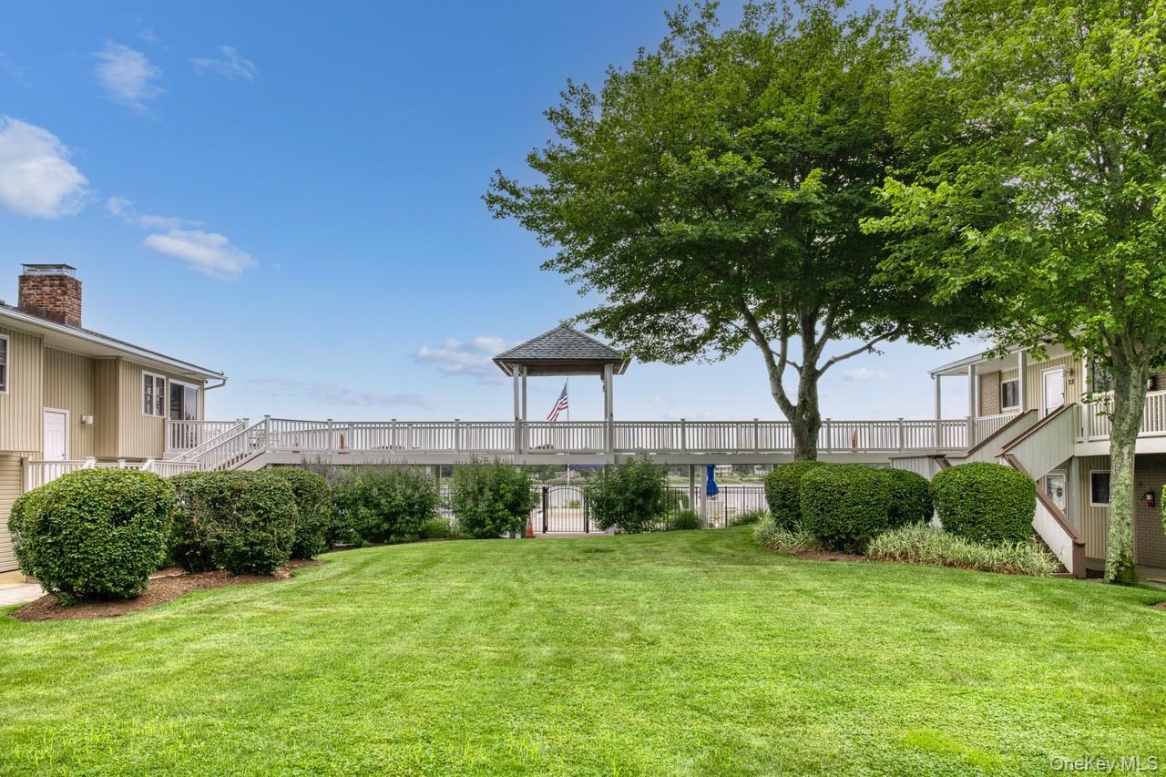 61 West Tiana Road, Unit 6 Hampton Bays, NY 11946 - Photo 2 of 10 a front view of a house with a yard and garage