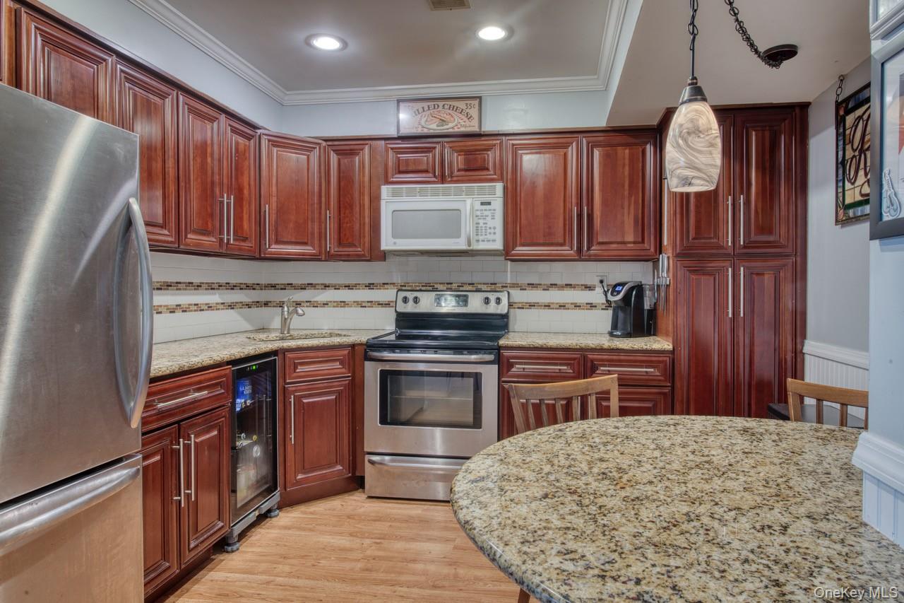 61 West Tiana Road, Unit 6 Hampton Bays, NY 11946 - Photo 3 of 10 a kitchen with stainless steel appliances granite countertop wooden cabinets a stove top oven a sink and dishwasher a oven with wooden cabinets