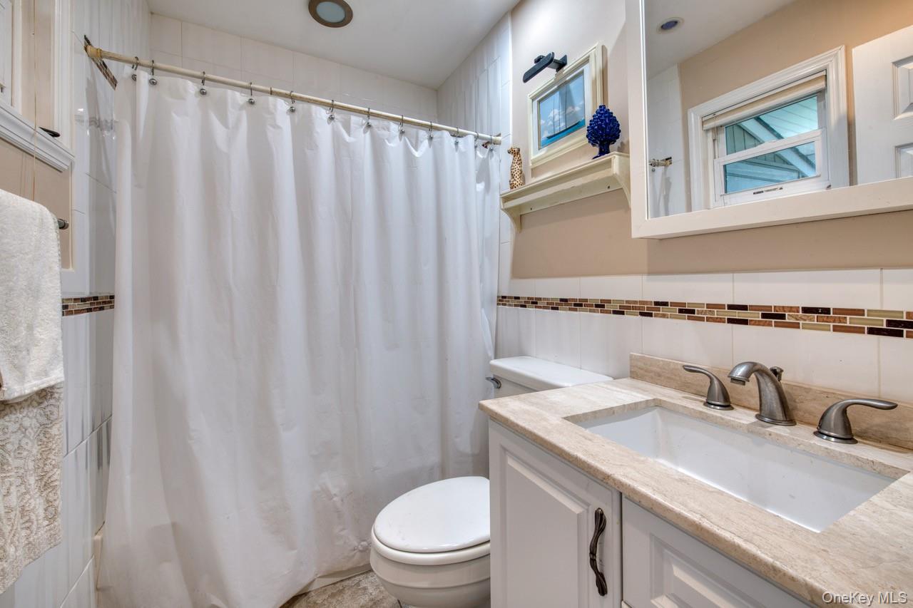 61 West Tiana Road, Unit 6 Hampton Bays, NY 11946 - Photo 6 of 10 a bathroom with a granite countertop sink and a toilet