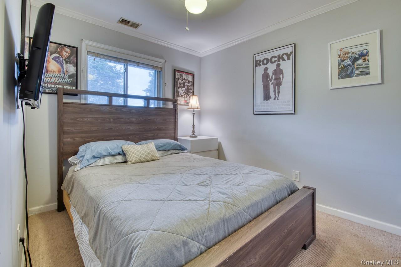 61 West Tiana Road, Unit 6 Hampton Bays, NY 11946 - Photo 7 of 10 a bed sitting in a bedroom next to a window