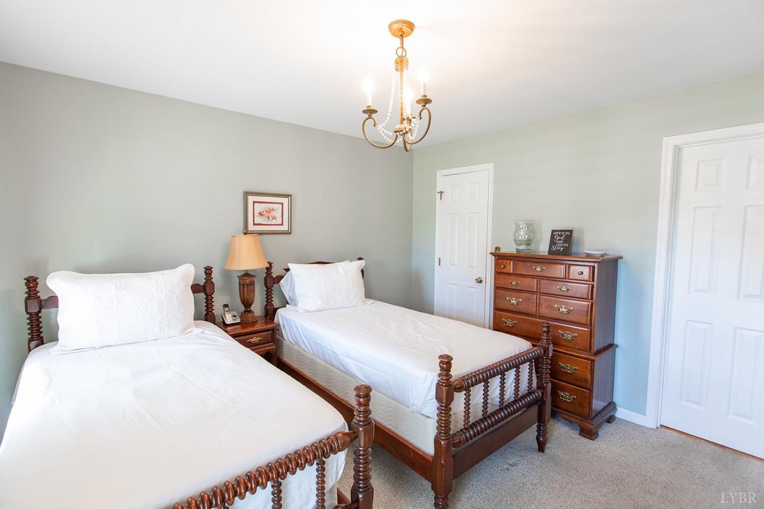115 Hunters Creek Road Forest, VA 24551 - Photo 22 of 43 a bedroom with two beds and a chandelier