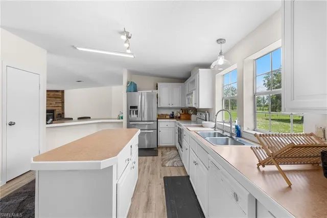 a large kitchen with kitchen island a large window a sink and stainless steel appliances
