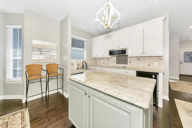 a kitchen with stainless steel appliances granite countertop a stove top oven a sink a dining table and chairs with wooden floor