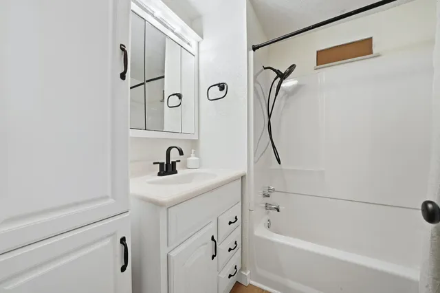 a bathroom with a granite countertop sink a mirror and a bathtub