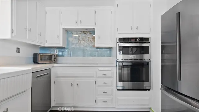a view of a kitchen with white cabinets and wooden floor