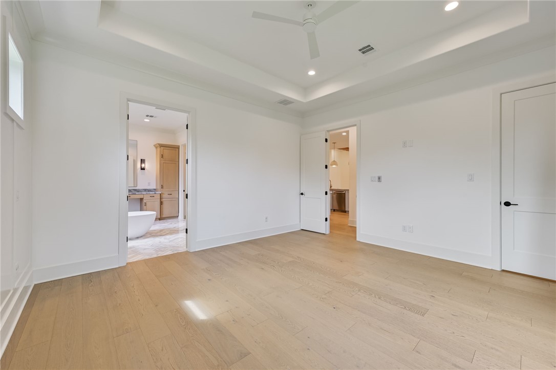 5115 Inverness Drive Bryan, TX 77802 - Photo 13 of 28 Primary bedroom featuring light wood-finish flooring, a tray ceiling with a ceiling fan, and large black-framed windows