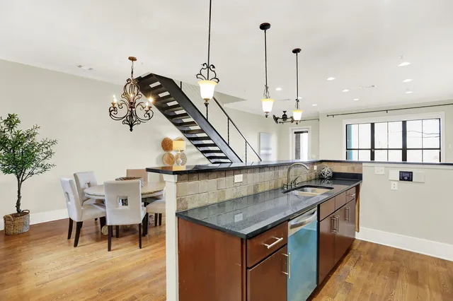 a kitchen with a table a chandelier and living room