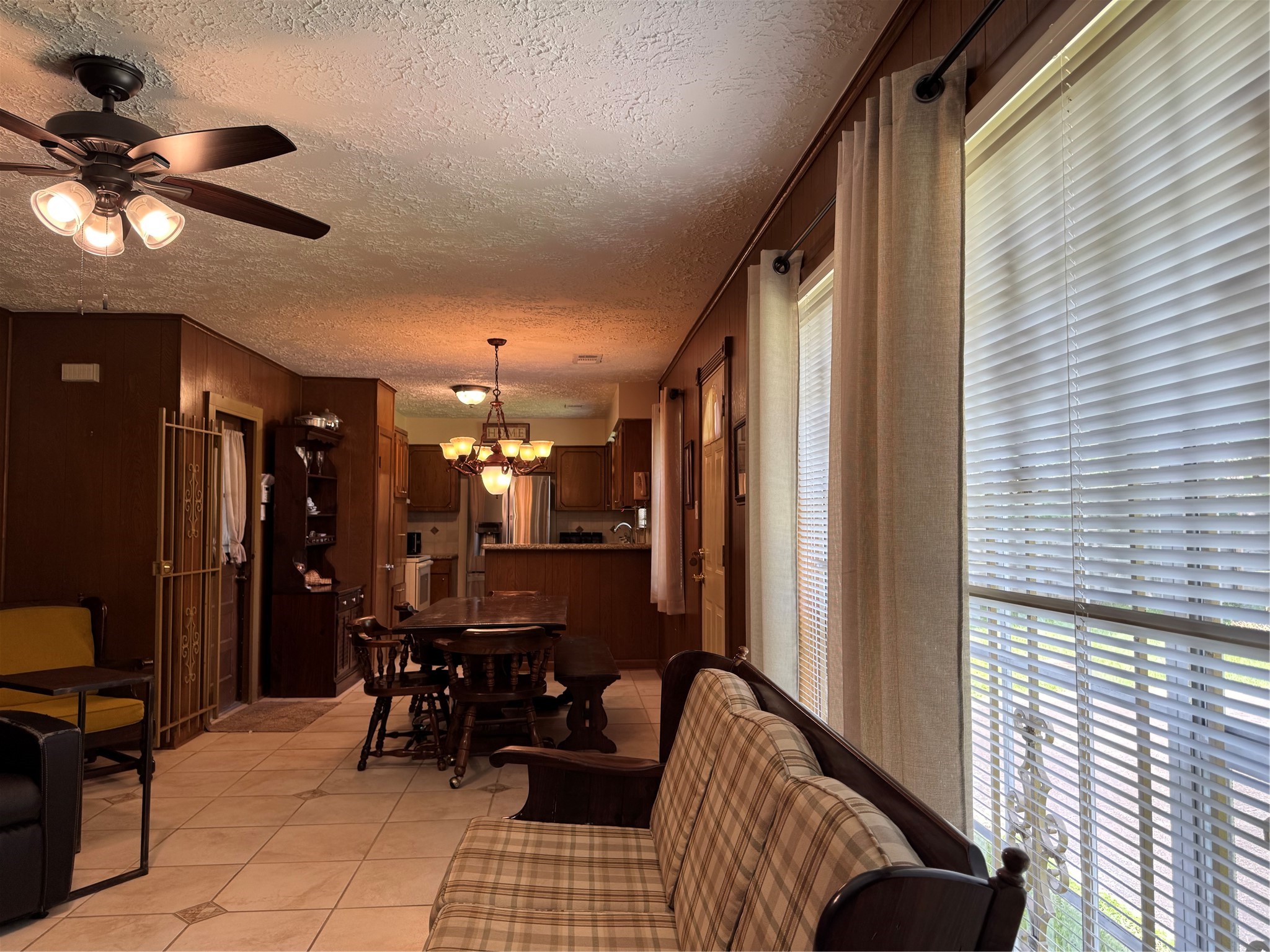 203 East Thornton Road Houston, TX 77022 - Photo 5 of 18 Cozy living space features an open layout with a dining area and kitchen, complemented by warm wood paneling and large windows for natural light.