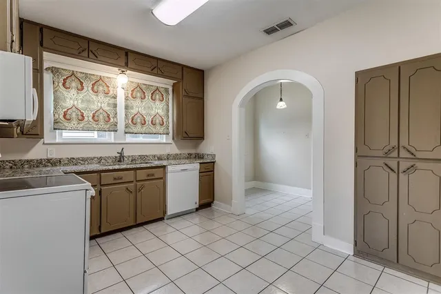 a view of a kitchen with kitchen island granite countertop a stove top oven microwave and a refrigerator