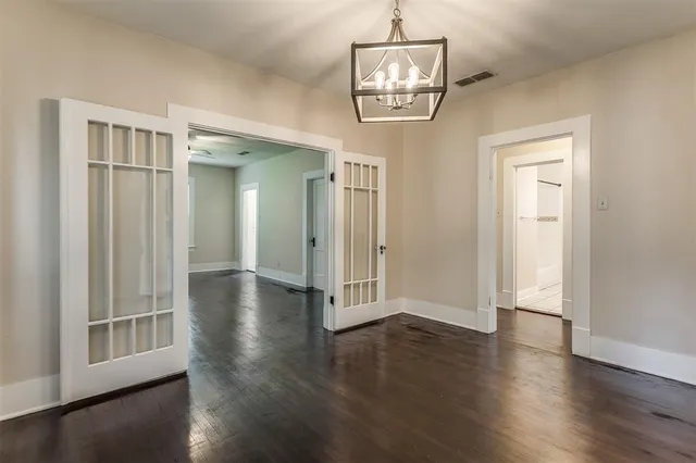 an empty room with wooden floor mirror and windows