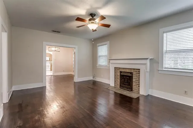 an empty room with wooden floor fireplace and windows
