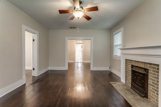 a view of empty room with wooden floor fireplace and fan