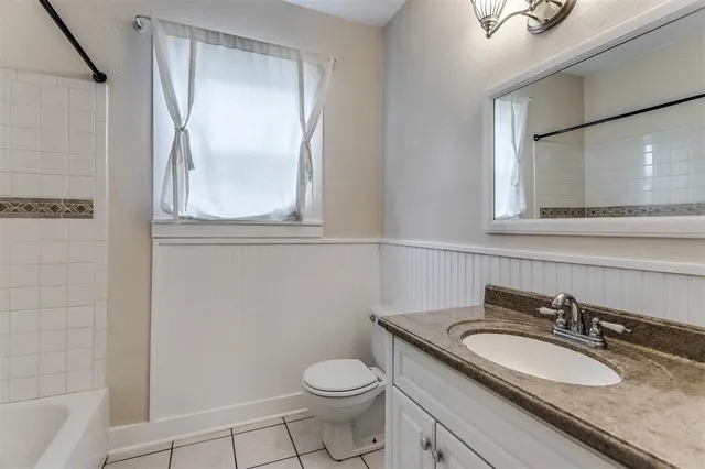 a bathroom with a granite countertop sink toilet and mirror