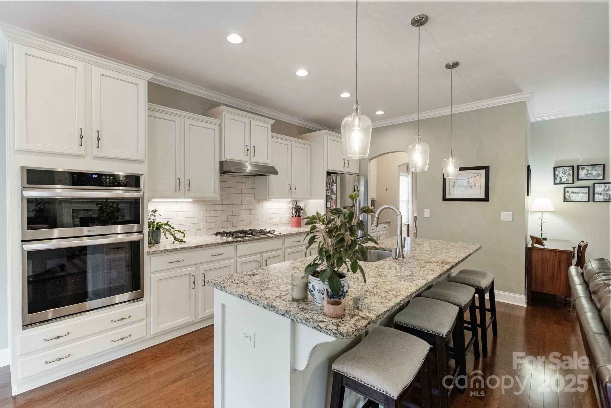 2304 Celandine Way Tega Cay, SC 29708 - Photo 12 of 47 a kitchen with granite countertop kitchen island stainless steel appliances a stove a sink a refrigerator cabinets and living room view
