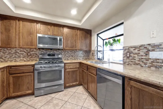 a kitchen with granite countertop a stove sink and microwave