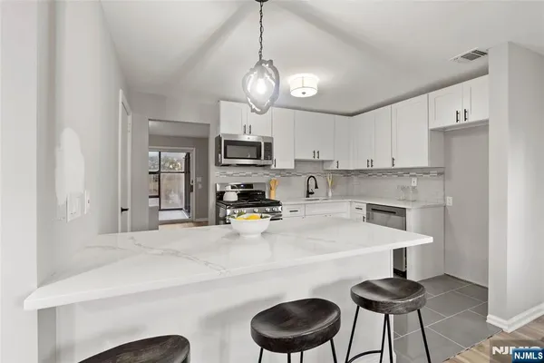 a kitchen with stainless steel appliances granite countertop a sink a stove a refrigerator cabinets and chairs
