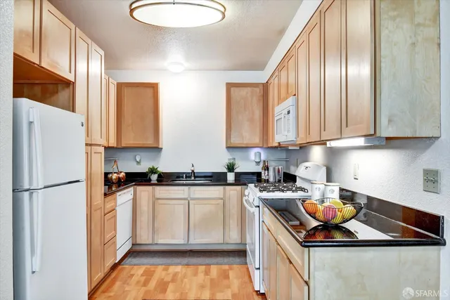 a kitchen with stainless steel appliances granite countertop a sink a stove and white cabinets