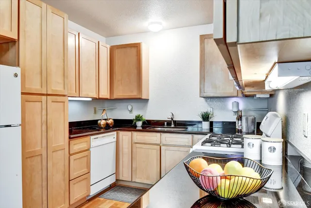 a kitchen with stainless steel appliances granite countertop a refrigerator a stove a sink dishwasher a microwave oven with white cabinets and wooden floor