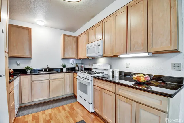 a kitchen with granite countertop white cabinets and appliances