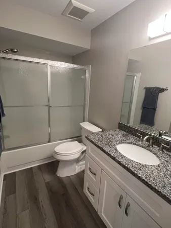 a bathroom with a granite countertop toilet sink and mirror