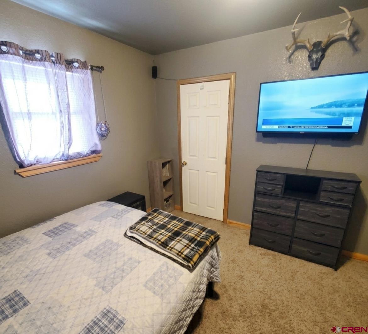 816 Main Street Manassa, CO 81141 - Photo 15 of 23 a bedroom with a bed and a flat screen tv