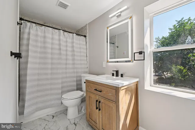 a bathroom with a granite countertop sink a toilet and a mirror