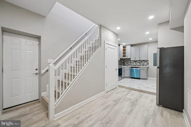 a view of a kitchen with wooden floor electronic appliances and stairs